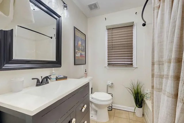 A vintage travel poster adds character to this bathroom at Ola's Oasis, a Savannah, GA vacation rental.