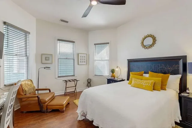 A leather armchair beside mustard-hued pillows makes a reading nook in this bedroom at Ola's Oasis in Savannah, GA.