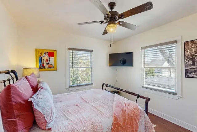 Soft pink bedding and a vintage iron frame welcome guests to this cheerful bedroom at Ola's Oasis in Savannah, GA.