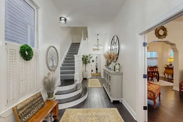 A grand staircase and warm entryway welcome guests to Ola's Oasis, a historic Savannah, GA vacation rental.
