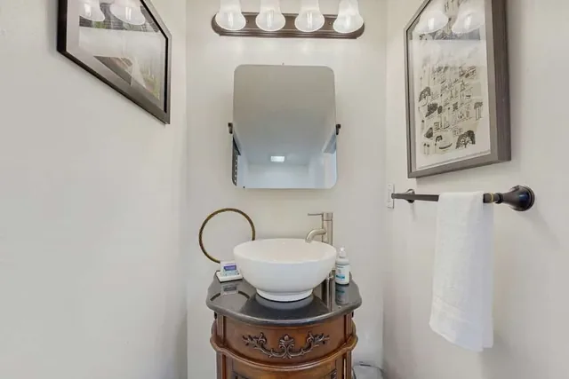 An antique washstand topped with a vessel sink gives this powder room at Ola's Oasis in Savannah, GA its distinctive charm.