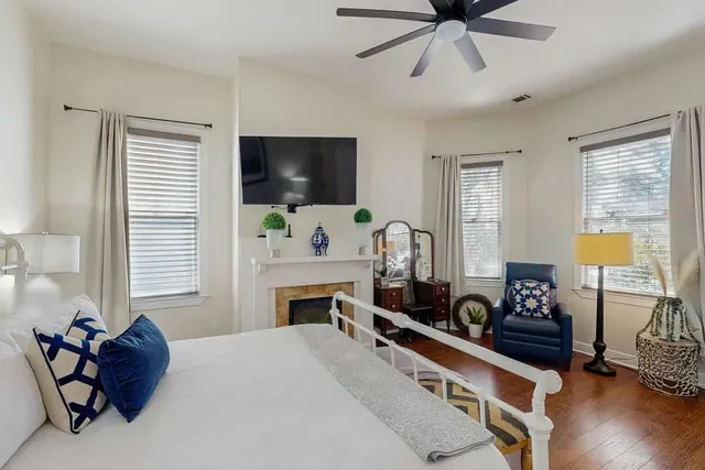 Spacious primary bedroom with a decorative fireplace and mounted TV at Ola's Oasis, a Savannah, GA vacation rental.